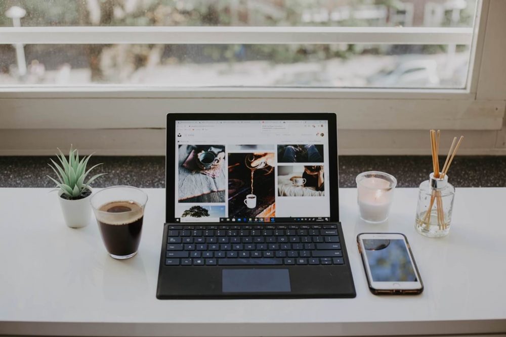 White Desk with cell phone, laptop and coffee.